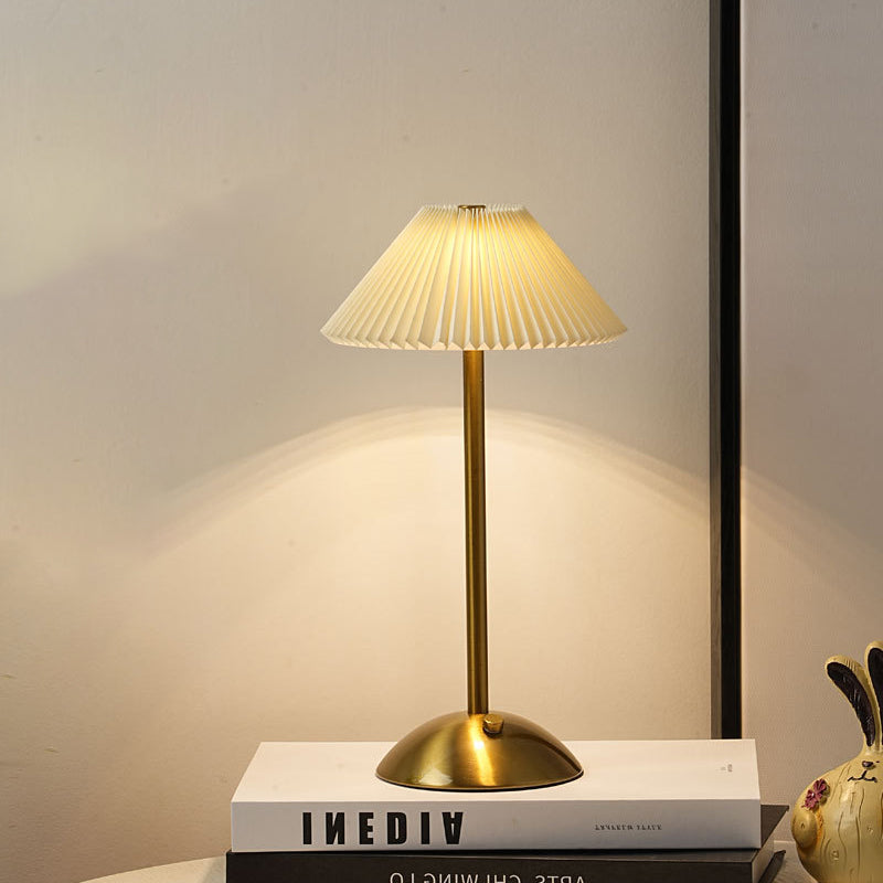 Full-height gold table lamp with tall pleated shade on white