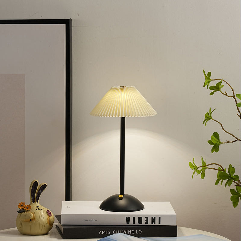 Warm glow escaping the pleats of the lit gold table lamp shade