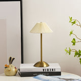Gold table lamp with cream pleated shade styled on a nightstand