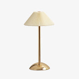 Tall gold table lamp with cream conic pleated shade on white