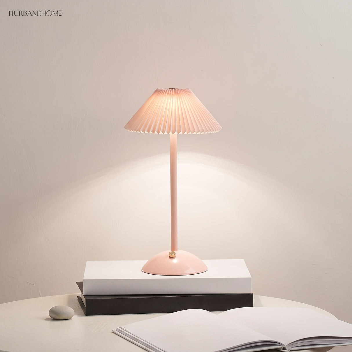 Pink pleated table lamp glowing warm with a control button on its domed base