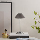 Silver base table lamp with grey pleated shade by a framed print