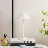All white table lamp with pleated shade styled on a bright shelf