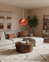 Copper molten pendant lit above a beige living room with a curved sofa