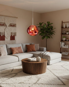 Copper molten pendant lit above a beige living room with a curved sofa