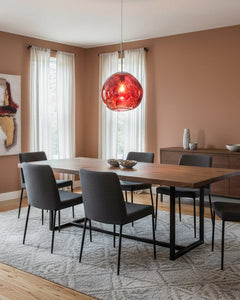 Copper molten pendant hanging above a dark dining table in a warm toned room