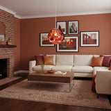 Copper pendant glowing in a terracotta living room beside a brick fireplace