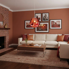 Copper pendant glowing in a terracotta living room beside a brick fireplace