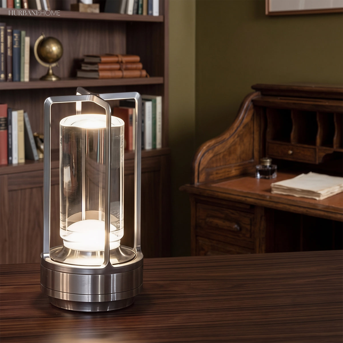 Silver cordless table lamp glowing on a wooden desk in a green study