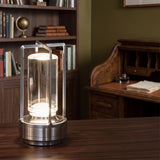 Silver cordless table lamp glowing on a wooden desk in a green study