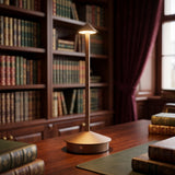 Cordless brown LED table lamp glowing on a wooden library desk