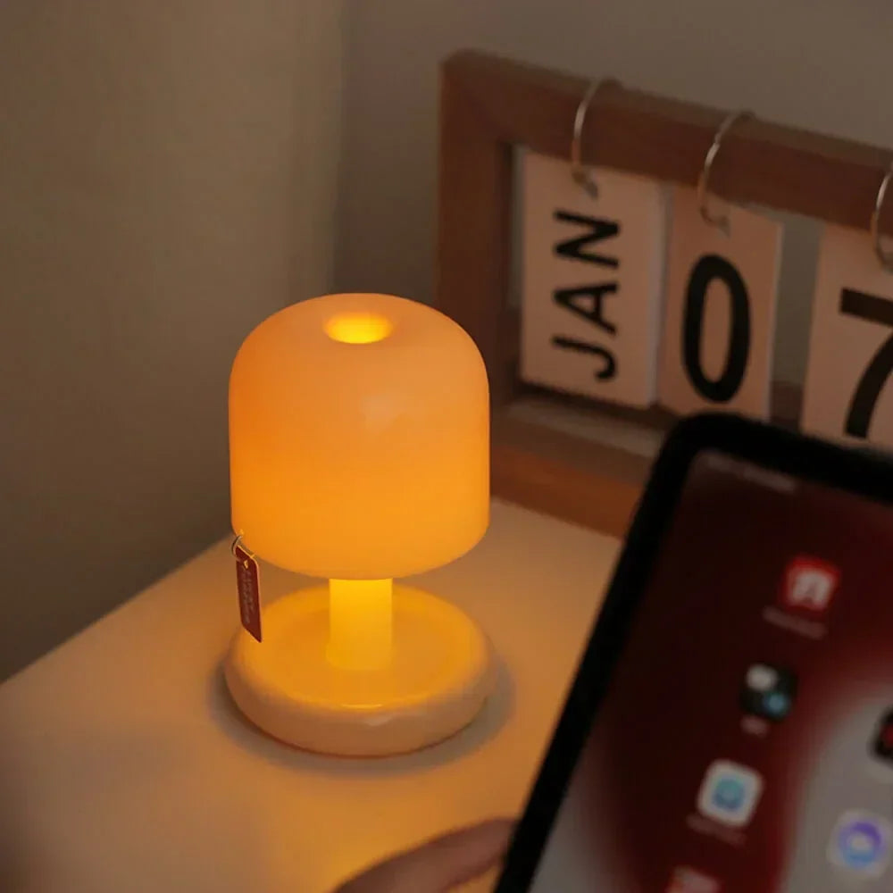 Small cordless lamp glowing on a desk beside a flip calendar and tablet