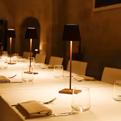 A row of cordless lamps lighting a long set banquet table