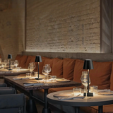 Cordless lamps on restaurant tables beside a white brick wall