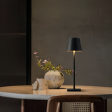 Black cordless lamp on a marble table against a fluted grey wall
