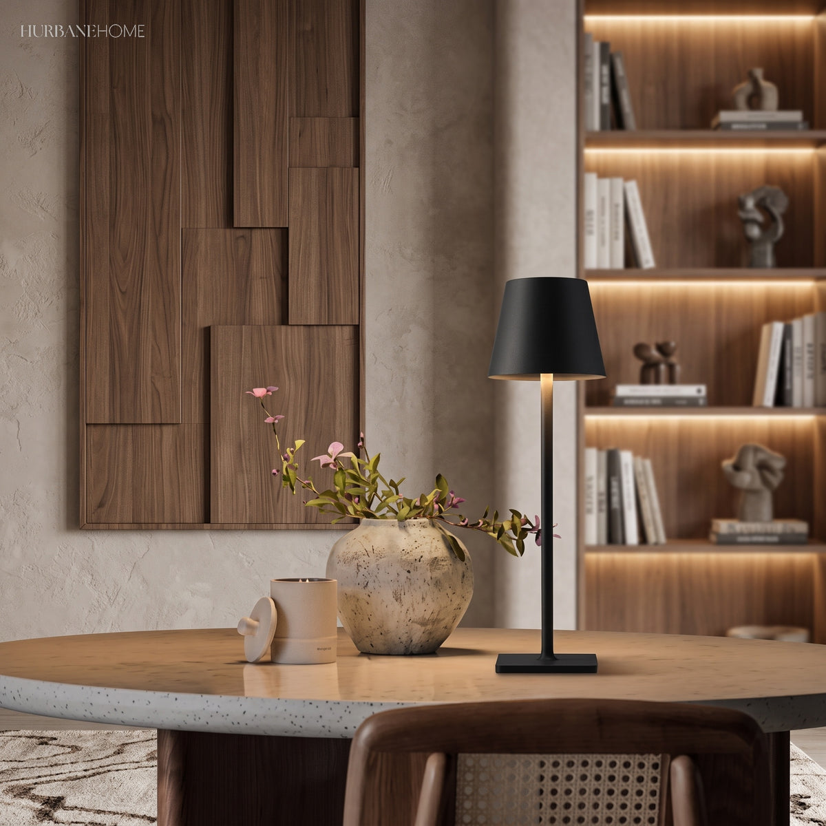 Black cordless lamp lighting a round dining table beside a styled shelf