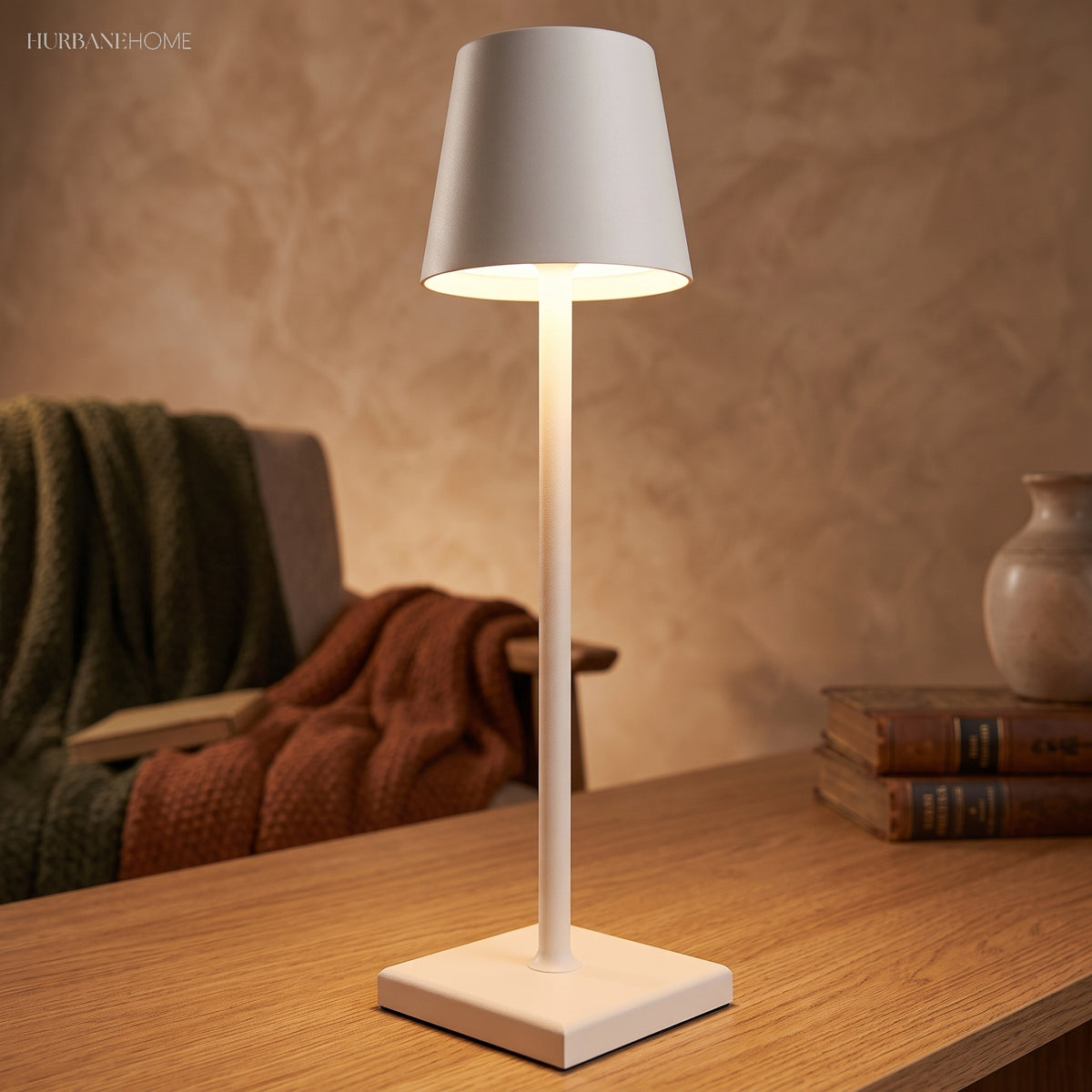 White cordless table lamp lighting a table beside a folded throw