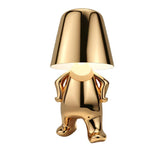 Gold figurine lamp standing upright holding the shade overhead