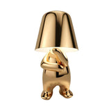 Gold figurine lamp standing with its arms folded across its chest