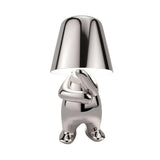 Silver figurine lamp standing with its arms folded across its chest