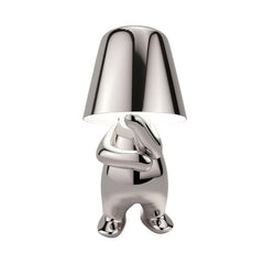 Silver figurine lamp standing with its arms folded across its chest