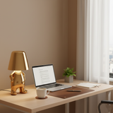 Gold figurine lamp lit on a desk beside a laptop and coffee