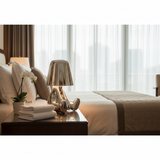 Gold figurine lamp lit on a bed with folded white towels