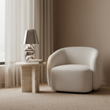 Silver figurine lamp lit on a stone side table beside an armchair