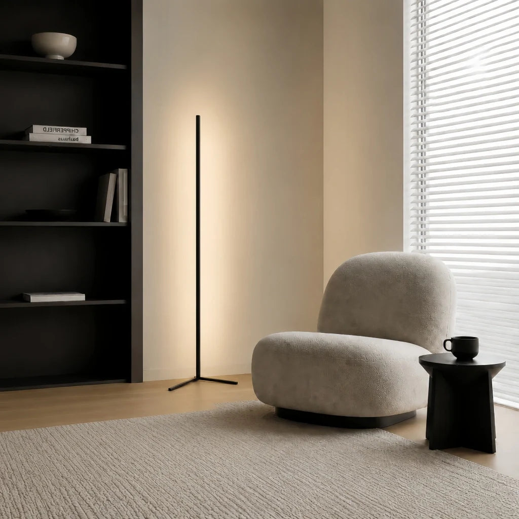 Black minimalist floor lamp beside a boucle chair, black bookcase and woven rug