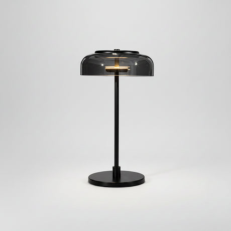 A modern table lamp with a black metal stand, round base, and a translucent dark gray dome shade, shown on a white background with its power cord visible.