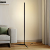 Black floor lamp with warm glow next to a grey sofa and curtain