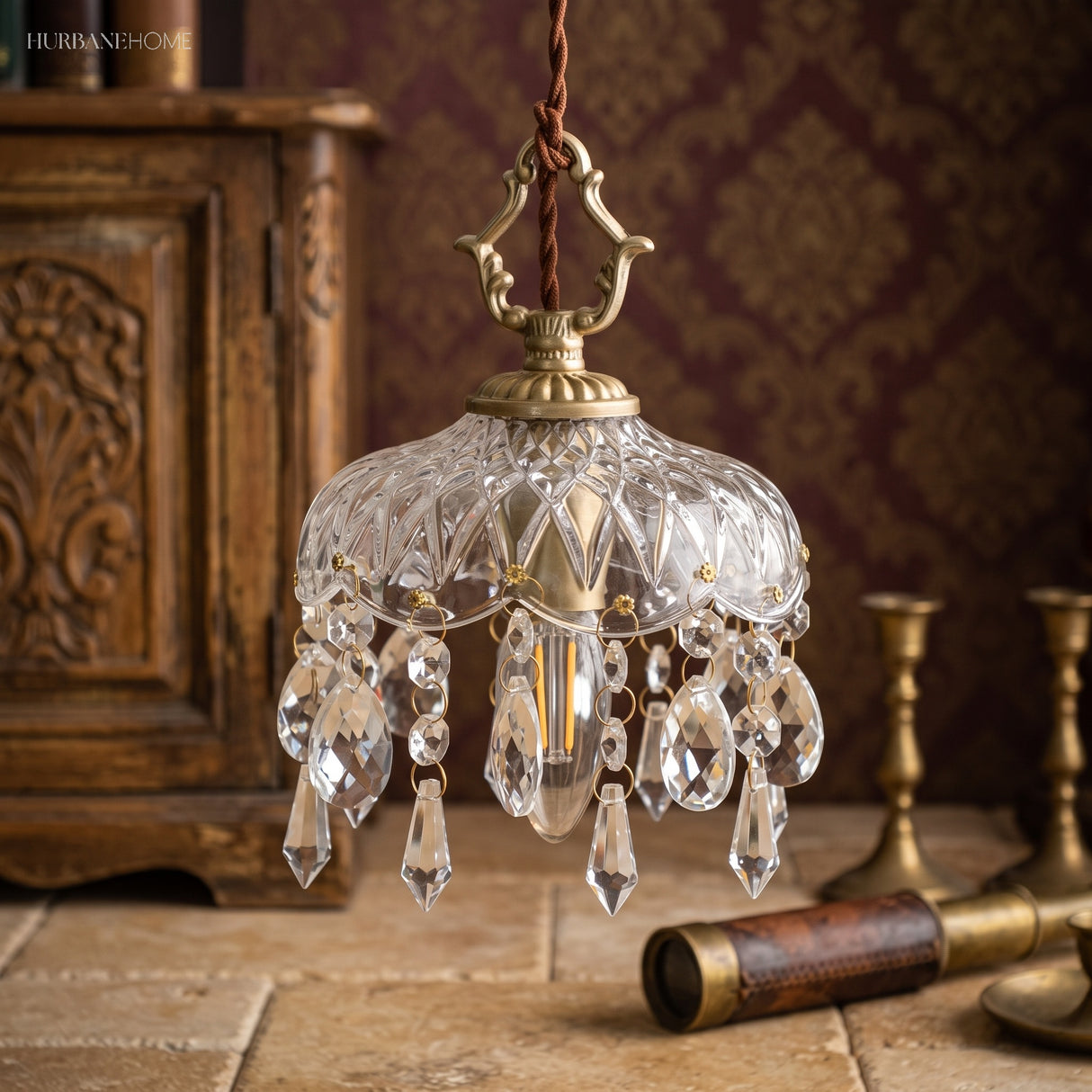 Crystal pendant light beside a carved wood cabinet with brass candlesticks