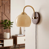 Cream dome glass sconce beside a mid-century console and potted plant