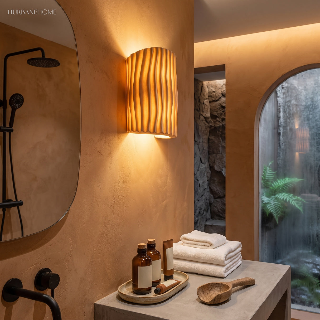 Cream wall sconce casting warm up and down light in a terracotta bathroom