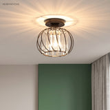 Black crystal cage ceiling light throwing starburst patterns above a green wall