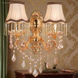 Gold crystal sconce with pleated fabric shades on damask wallpaper