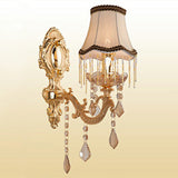 Single arm gold sconce with a fringed fabric shade and crystals