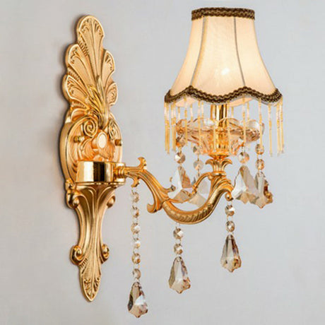 Gold single light sconce with a fringed fabric shade, studio view