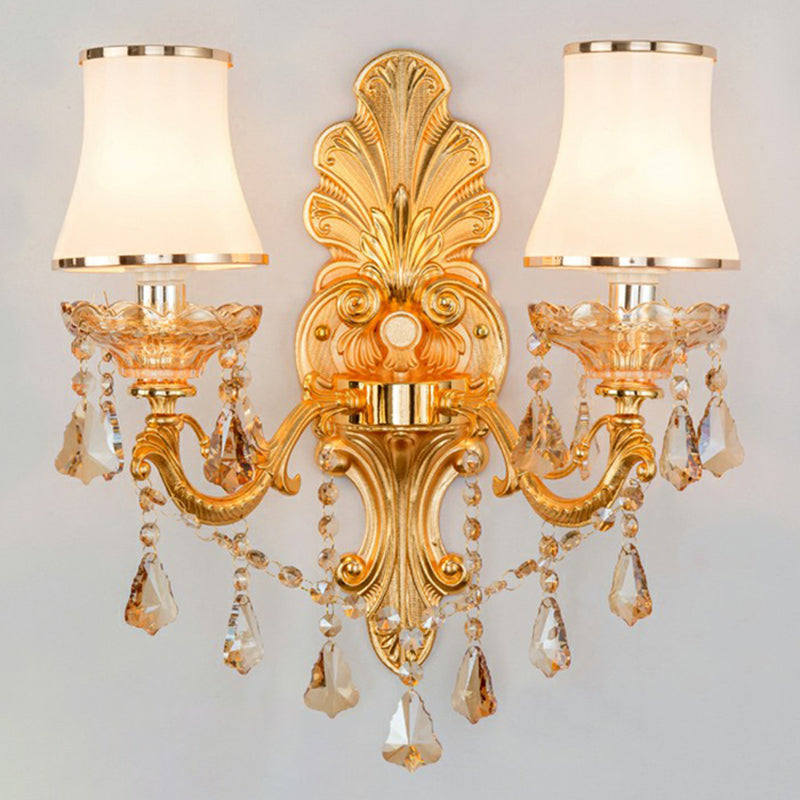 Lit gold two light sconce showing crystal drops and opal shades
