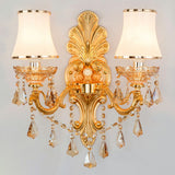 Lit gold two light sconce showing crystal drops and opal shades