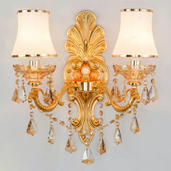 Lit gold two light sconce showing crystal drops and opal shades