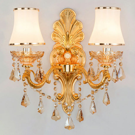 Lit gold two light sconce showing crystal drops and opal shades