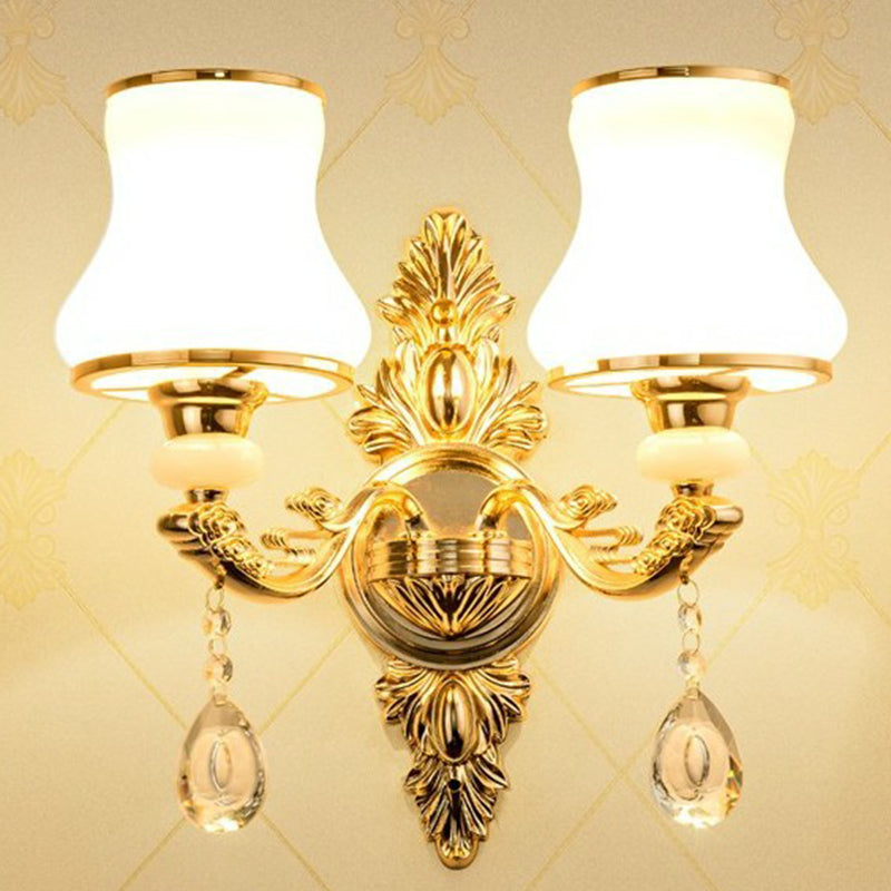 Gold two light sconce with opal glass shades on a cream backdrop