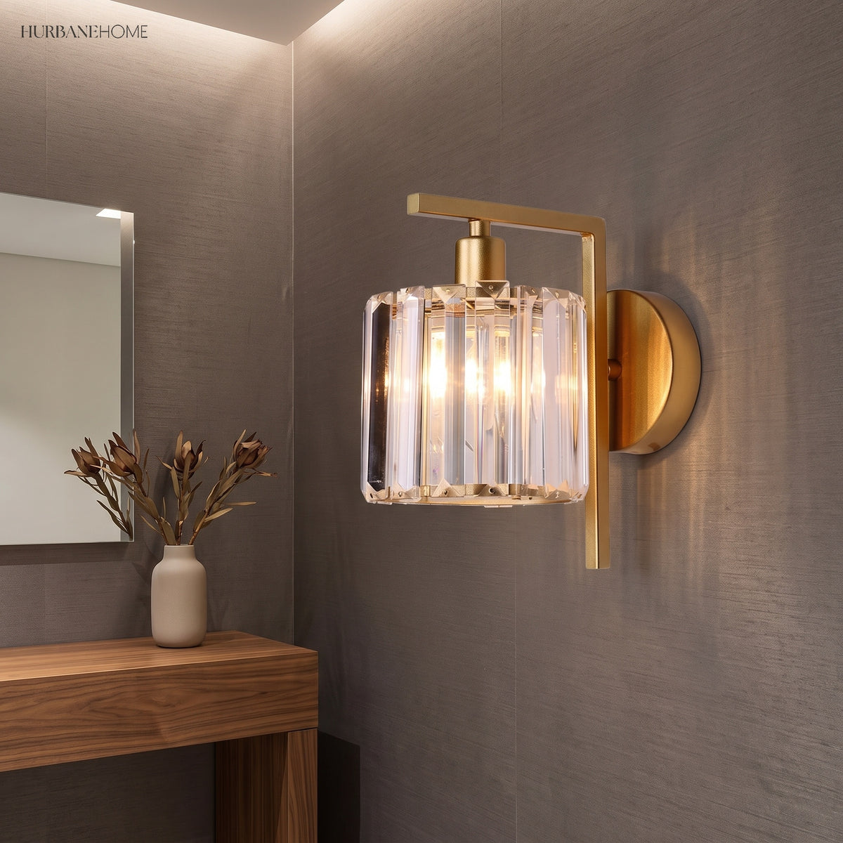 Crystal column sconce lit on a grey wall above a timber console