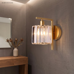 Crystal column sconce lit on a grey wall above a timber console