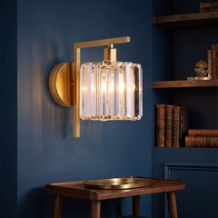 Gold sconce with a clear crystal column shade on a navy wall