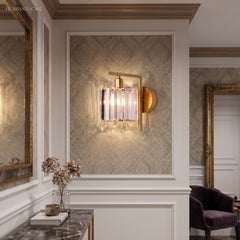 Crystal column sconce lit in a panelled hall beside a side table