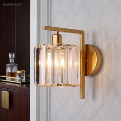 Crystal column sconce lit on a patterned wall beside a decanter