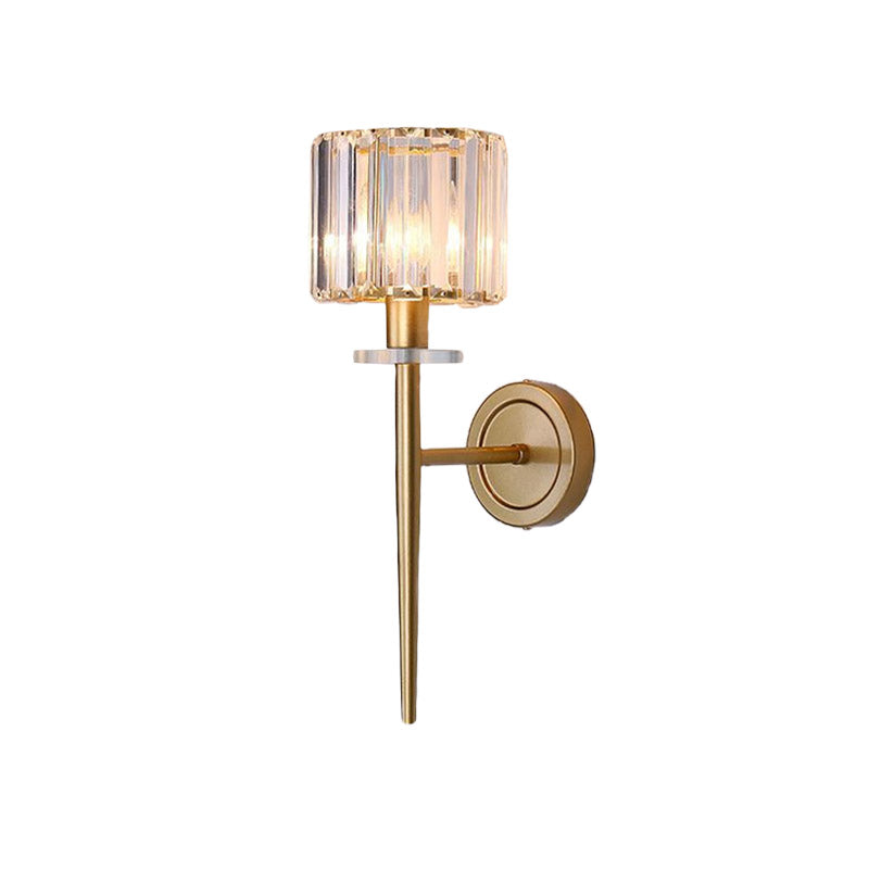 Gold sconce with a lit crystal shade on a plain cream wall