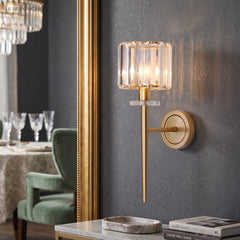 Crystal sconce lit beside a gilt mirror and a green armchair